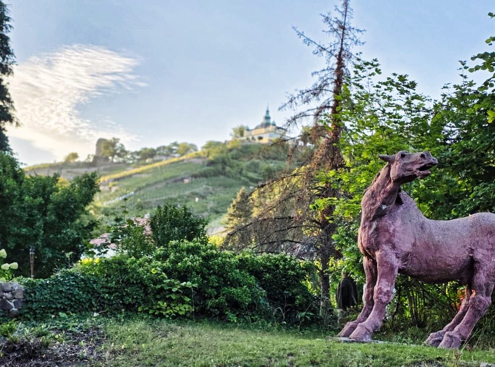 Pferdeskulptur in einem Garten in Radebeul mit Blick hinauf zum Spitzhaus